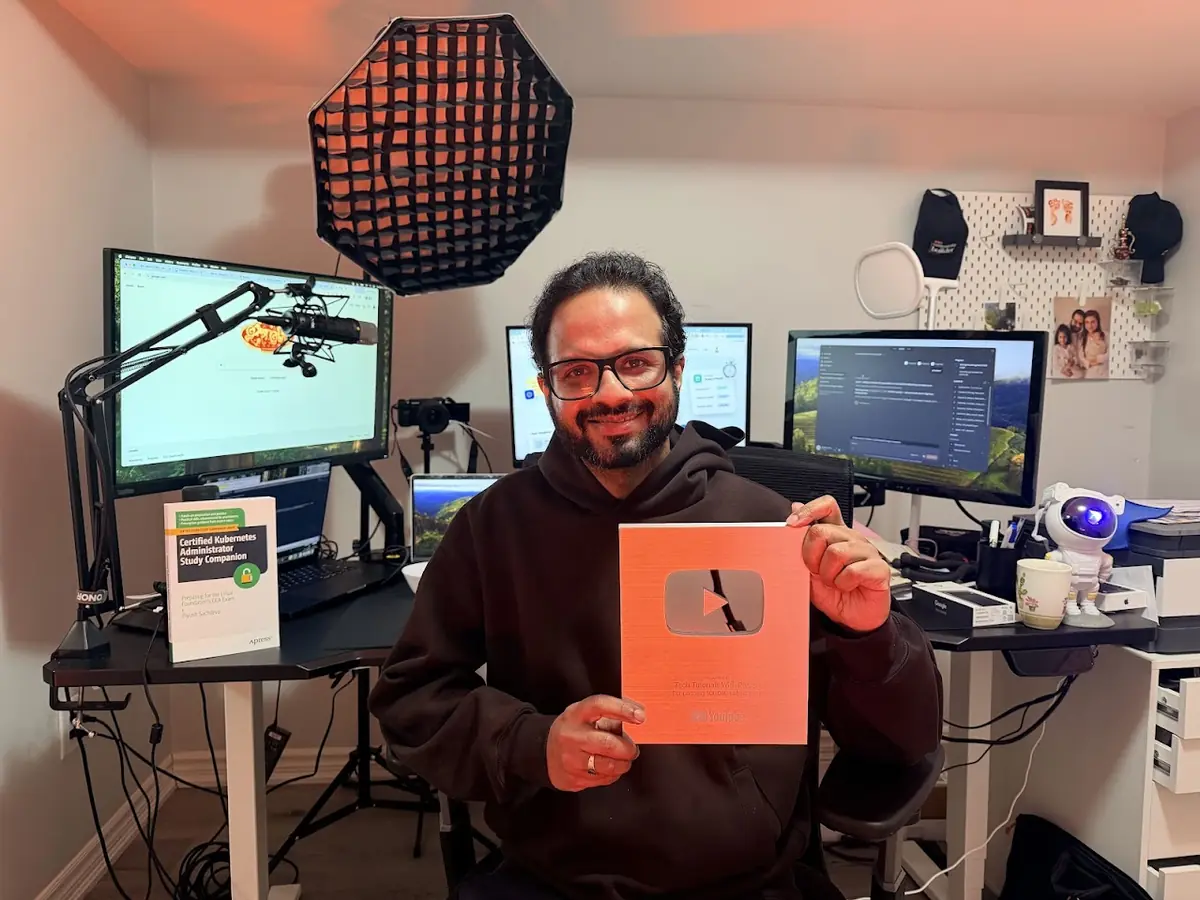 Piyush Sachdeva holding his YouTube Silver Creator Award, with his Apress book on the desk